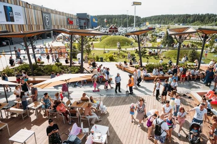 A terrace in front of a shopping centre in summer: people take exactly the places where there is shelter from the sun