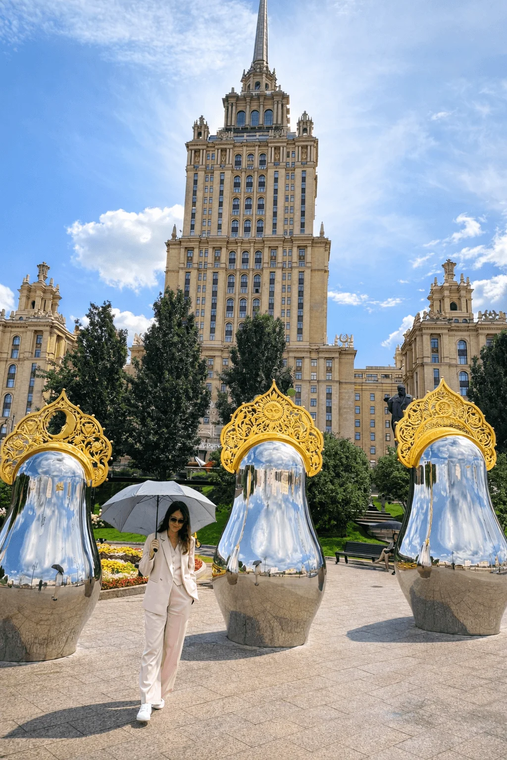 A guest photographs herself beside the mirror sculptures outside a hotel: the shot goes to her feed and works as advertising the hotel never paid for